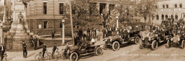 Mostly men are in this photo of a parade in a downtown.