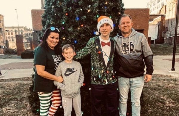 A photo of a family in front of a Christmas tree.