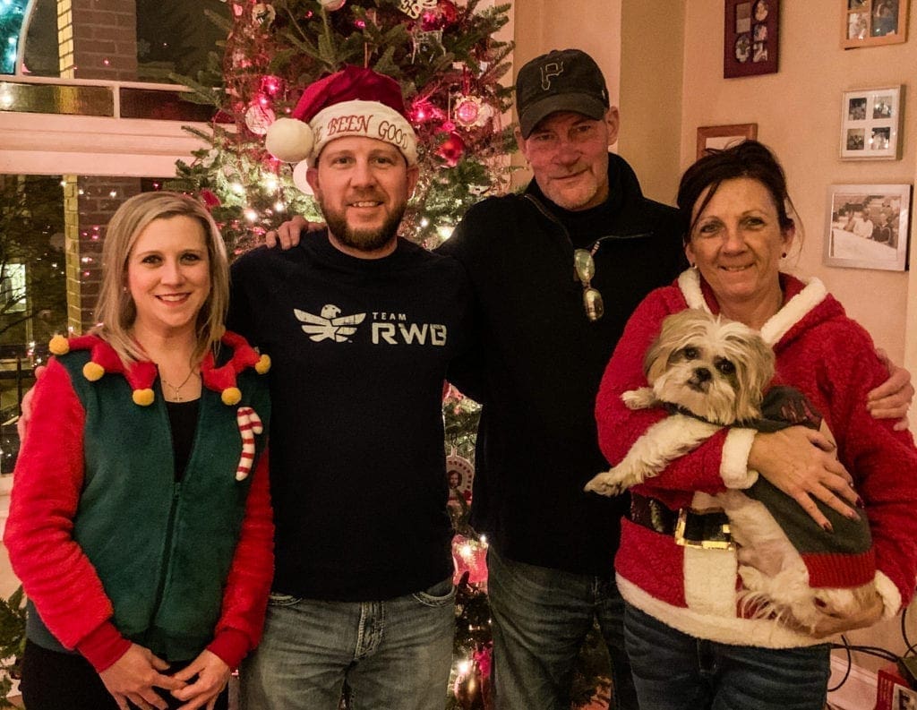 A photo of a family in front of their Christmas tree.