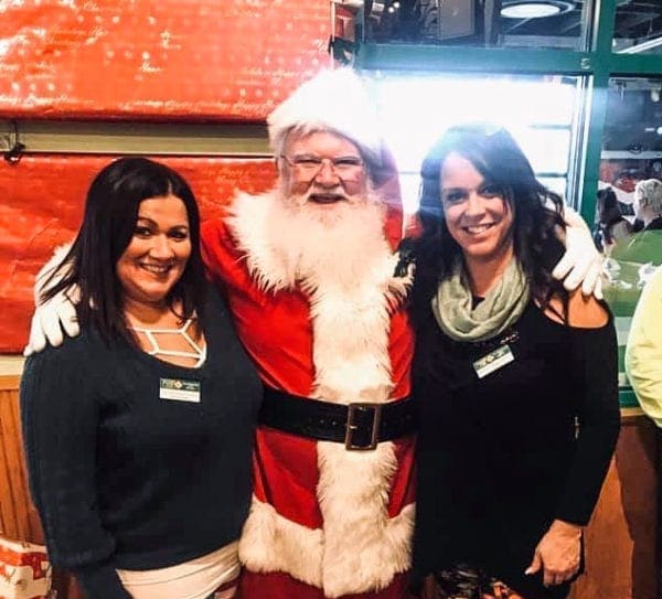 Santa posing with two pretty ladies at an eatery.