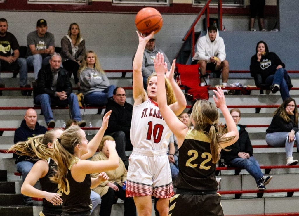 A female basketball player takes a jump shot.