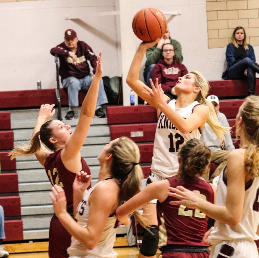 A girl going for a layup in a basketball game.