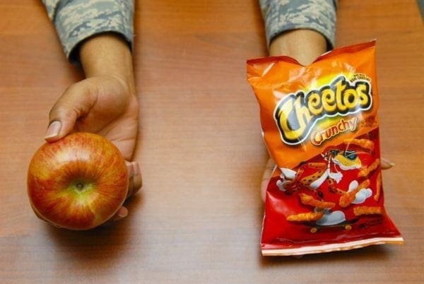 A photo of an apple and a bag of Cheetos.