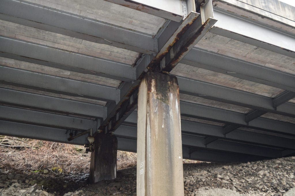 A rusted girder under an interstate.