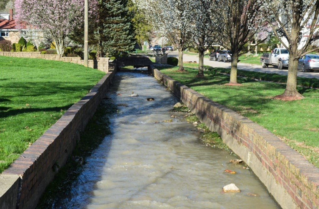 A photo of a stream lined with bricks.