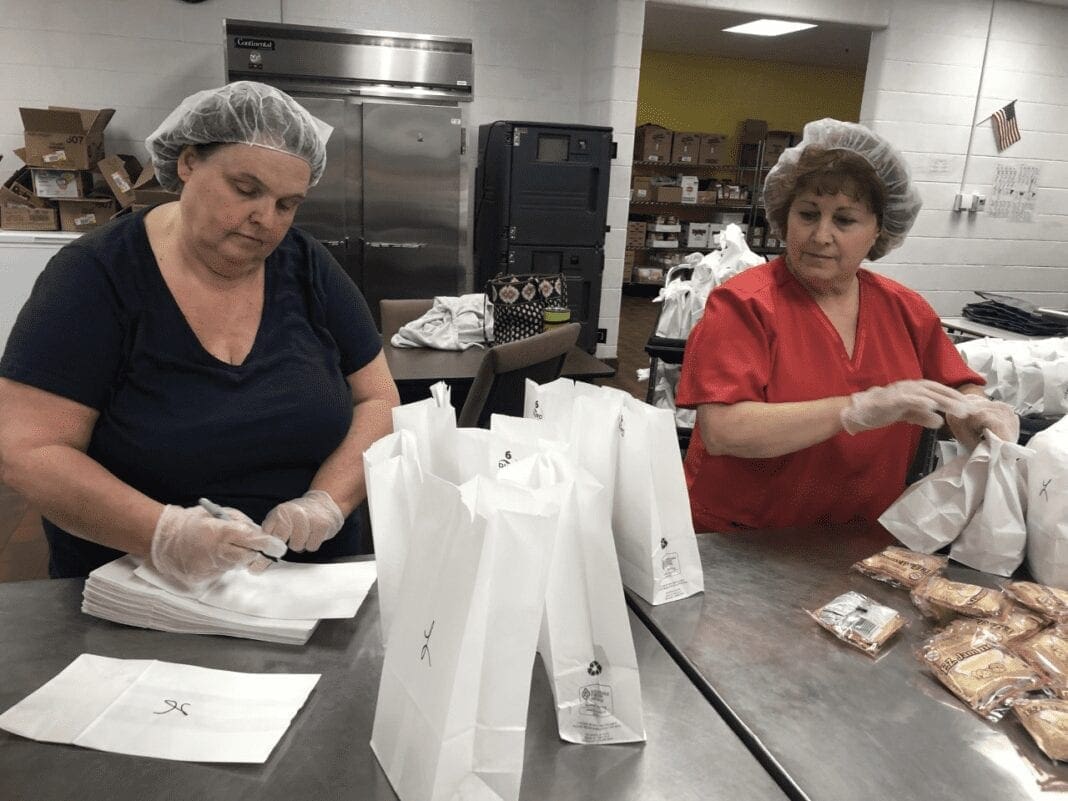 Two ladies packing lunches for students.