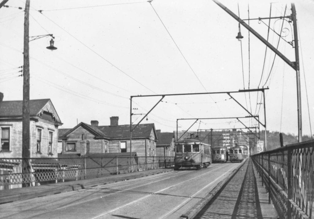 A historic photo of trolleys crossing a bridge.