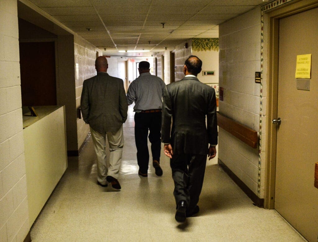 Three men walking down the hallway.