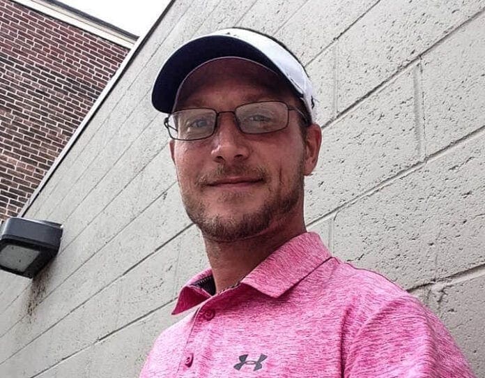 A photo of a white man in a pink shirt.