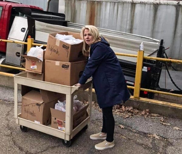 A blonde lady pushing a food cart.