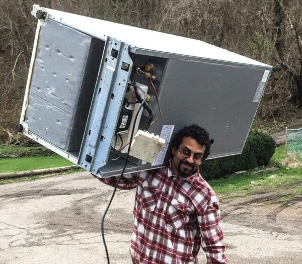 A man with a refrigerator on his shoulder.