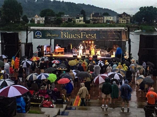 A photo of concert with fans using umbrellas.