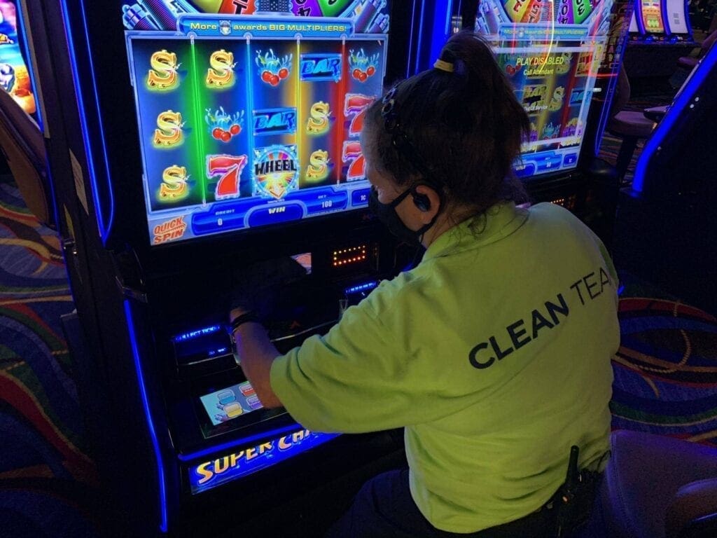 A staff member cleaning a gambling machine.