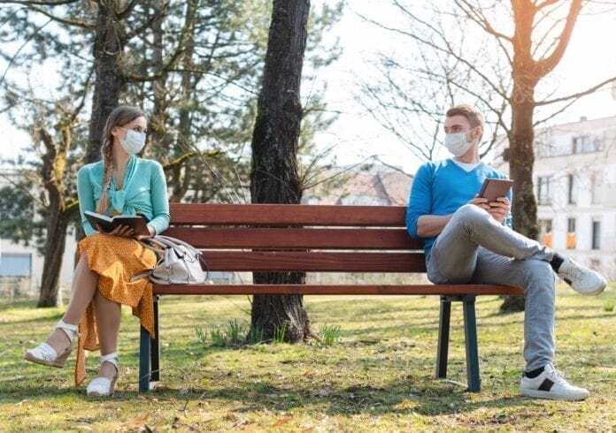 A man and woman on a bench in a park.