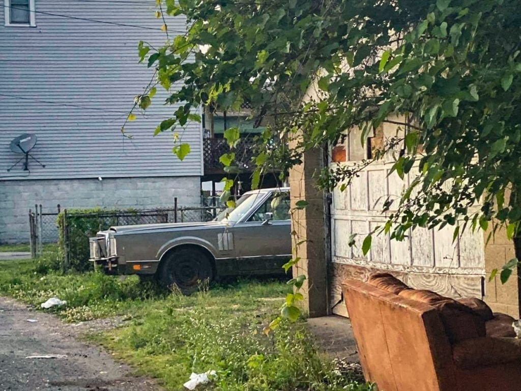 An abandoned car along an alley.