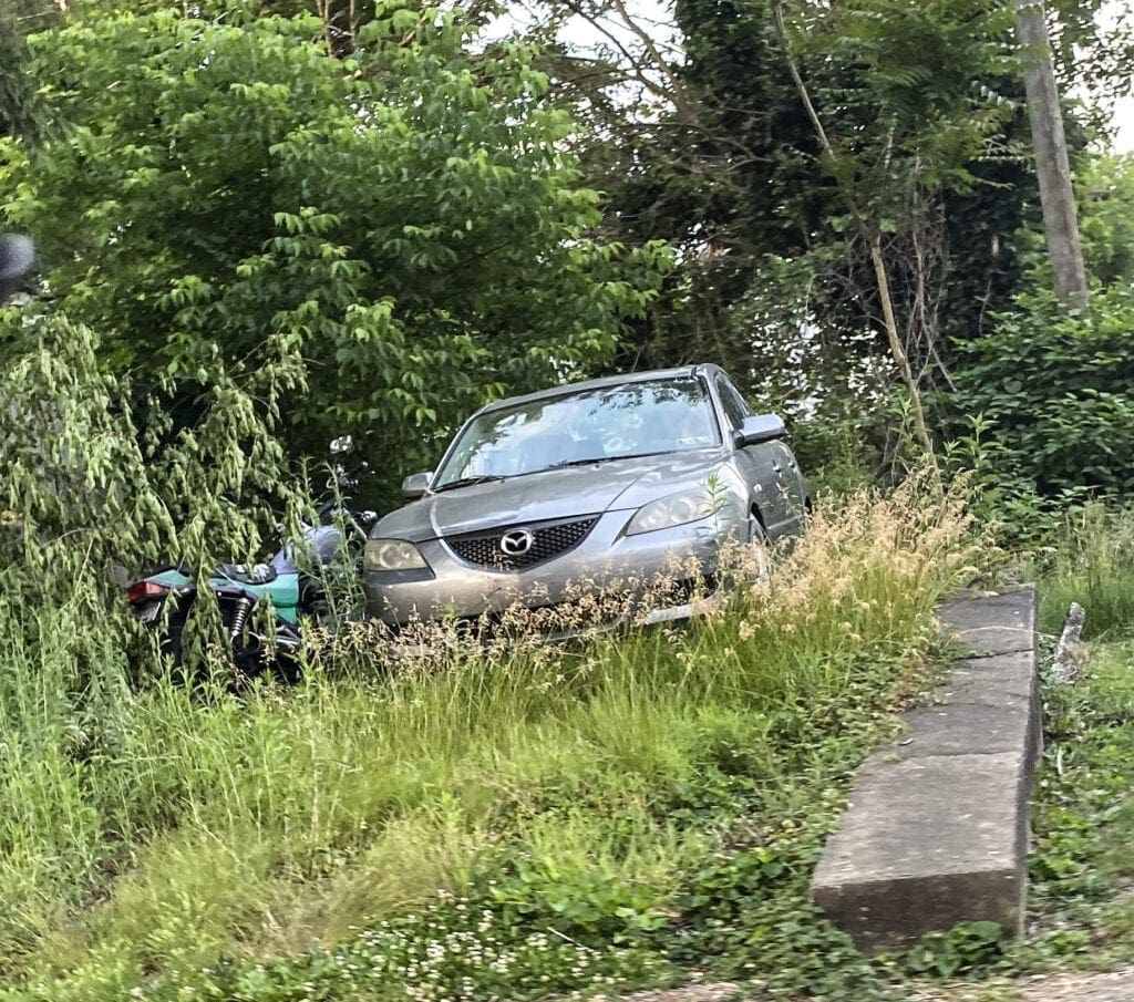 A grey car sitting in high grass.