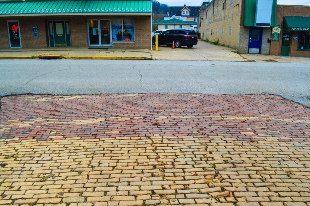 A brick road leading to an asphalt one.