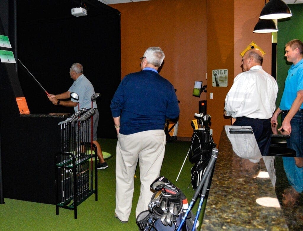 There are four men playing indoor golf.