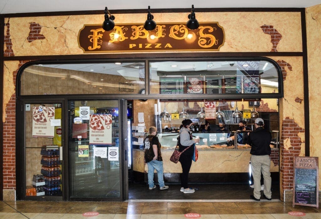 A photo of a pizza shop in a mall.