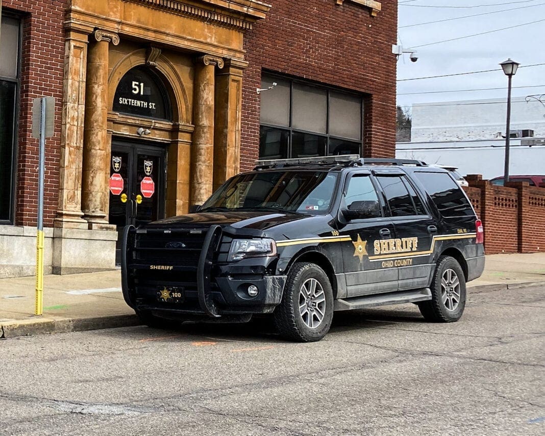 A photo of a black truck in front of a building.