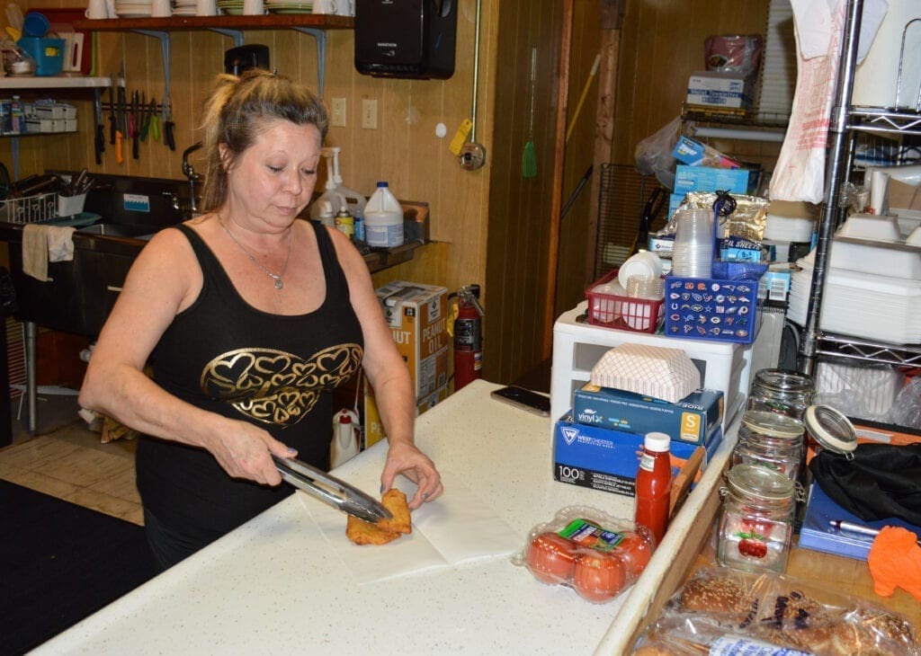 A lady making a fish sandwich.