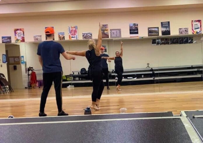 Two people dancing in front of mirrors.