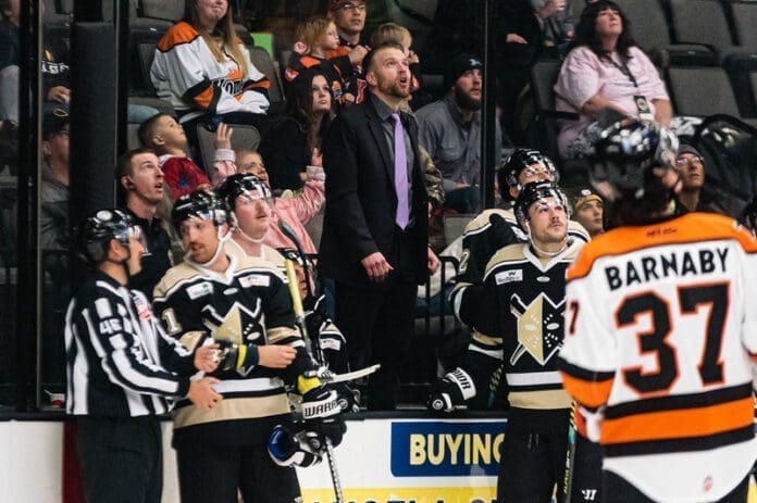 A young man behind a hockey bench.