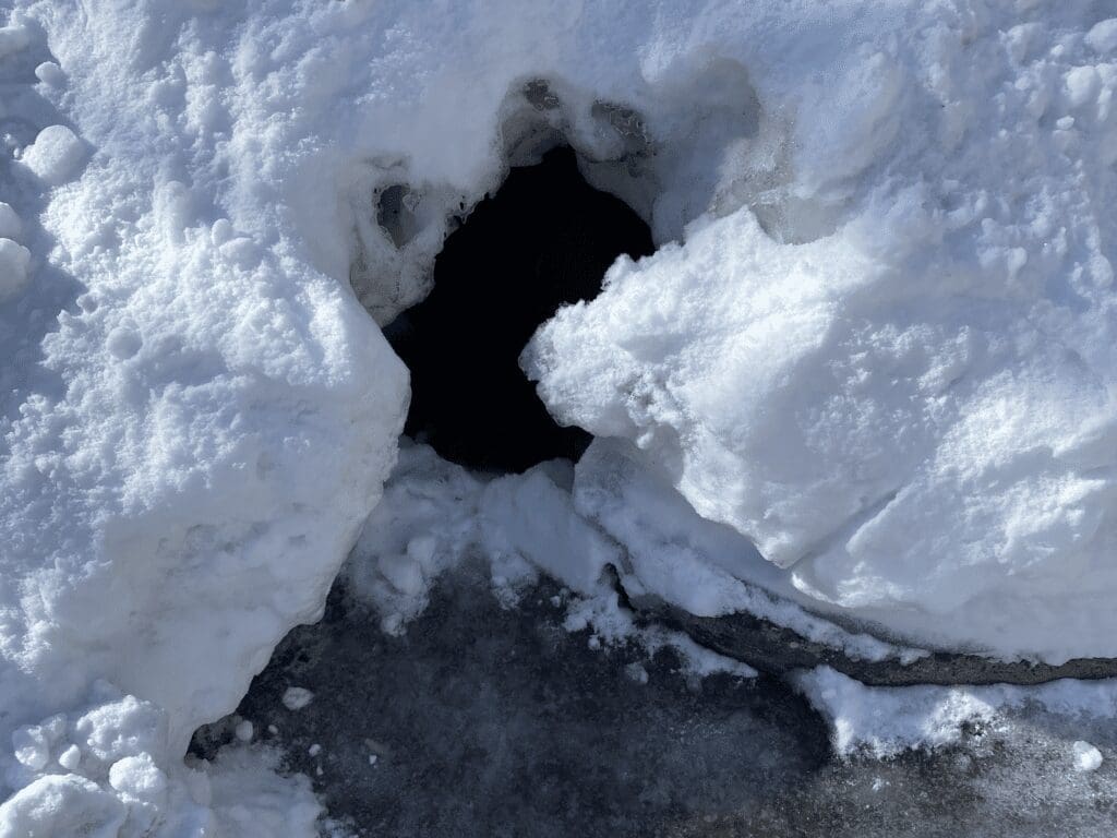 A pile of snow with a hole in it.