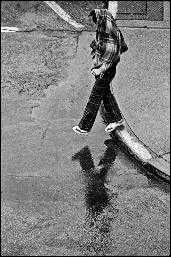 A boy stepping into a puddle.