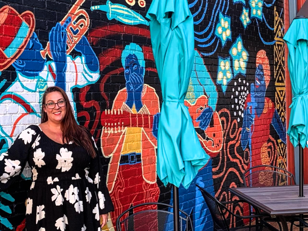 A lady in front of mural.