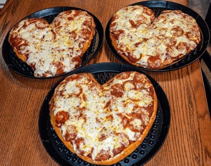 4FC84277-85C0-44E0-B8CD-FCEAF9E5DE58 There are three pizzas on a table.