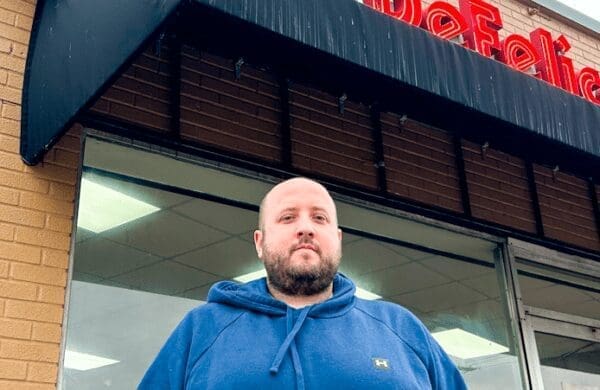 43BB9034-C57A-4979-BEF6-BF9D146EB67E A man in front of a building.