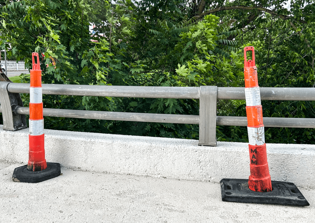 A sidewalk with two cones.