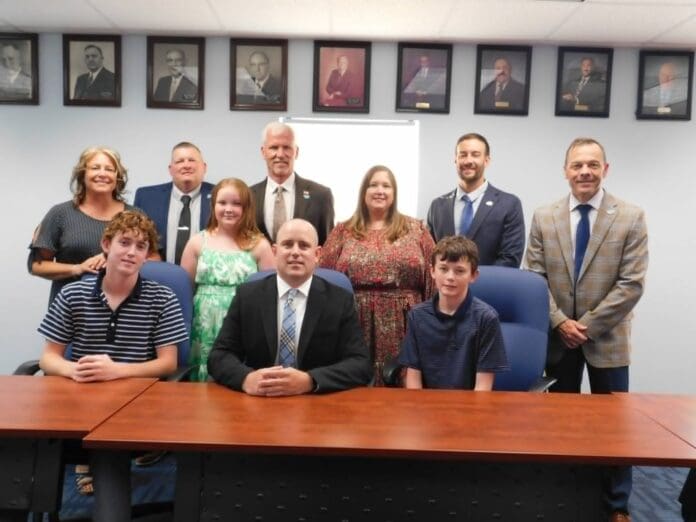 The Bridgeport Exempted Village School District welcomes David Nelson, hired as assistant treasurer as he prepares to take over managing the district finances. Nelson experience within the district and commitment to give his all for the Bulldogs cinched the post for him. Pictured seated are Nelson with sons, sophomore Connor, left, and eighth grader Trevor and daughter Kara, sixth grader, standing. Also standing from left are board members Kori Rosnick, Patrick McConnaughy, Don Cash, Karrie Puskas, Ryan Kreiter, and Superintendent Brent Ripley.